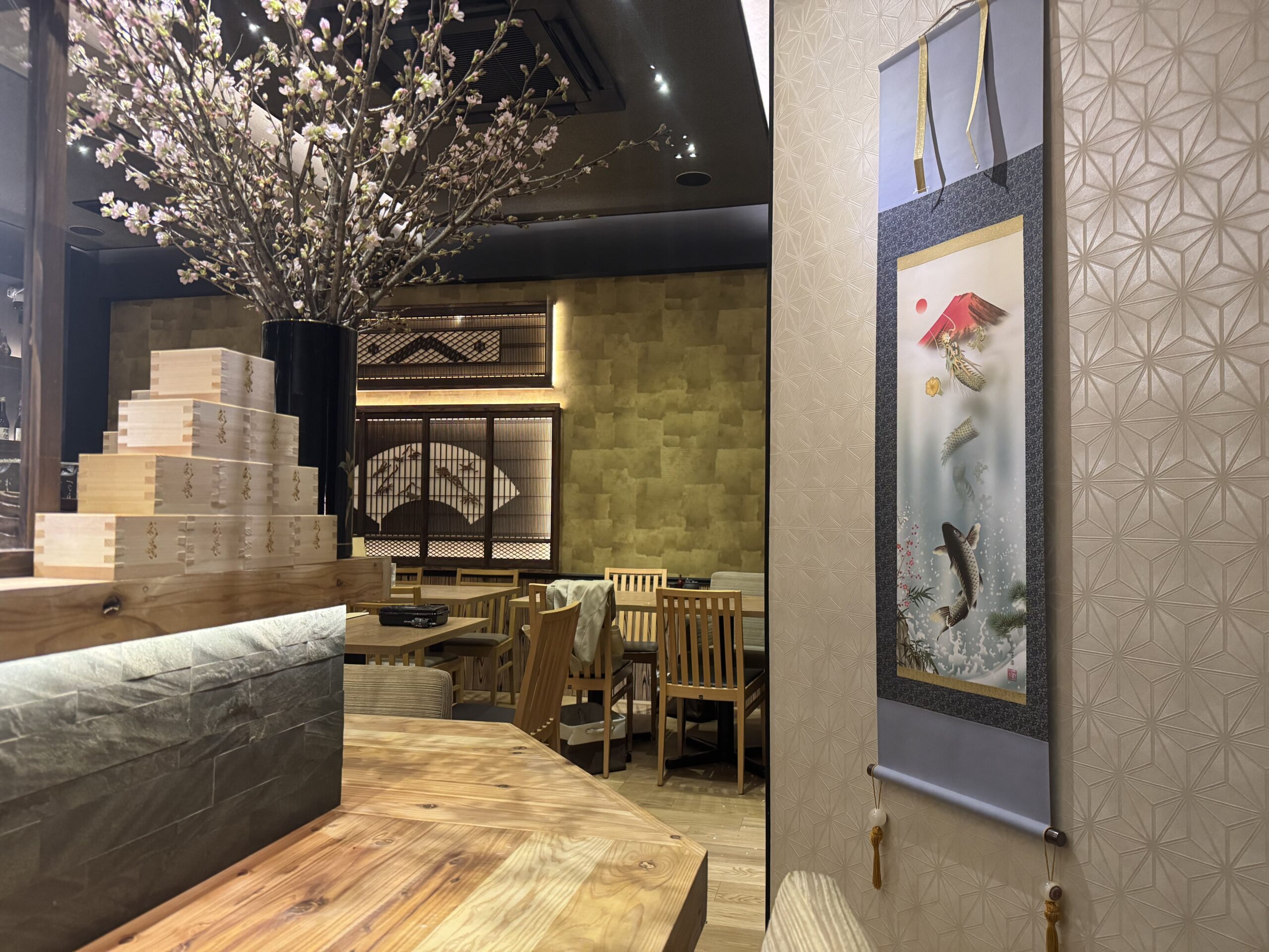 桜の枝が映える和モダンな店内と木製家具、掛け軸風の和アートが印象的な落ち着いた個室風空間